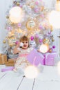 Cute little baby girl opening gift box with decorating christmas tree on background Royalty Free Stock Photo