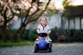 Cute little baby girl playing with blue small toy car in garden of home or nursery. Adorable beautiful toddler child Royalty Free Stock Photo