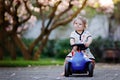Cute little baby girl playing with blue small toy car in garden of home or nursery. Adorable beautiful toddler child Royalty Free Stock Photo