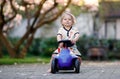 Cute little baby girl playing with blue small toy car in garden of home or nursery. Adorable beautiful toddler child Royalty Free Stock Photo