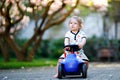 Cute little baby girl playing with blue small toy car in garden of home or nursery. Adorable beautiful toddler child Royalty Free Stock Photo