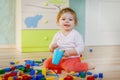 Cute little baby girl playing with educational toys. Happy healthy child having fun with colorful different wooden Royalty Free Stock Photo