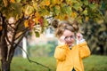 Little baby girl is playing with glasses and smiling outdoors.Sunny autumn day in the park, yellow light. soon to school Royalty Free Stock Photo