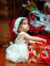 Cute little baby girl in Stana hat opens her first Christmas present Royalty Free Stock Photo