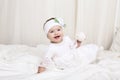 Cute little baby girl in white clothes, sitting on bed, playing with toy Royalty Free Stock Photo