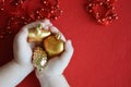 Small children`s hands hold a heart, a bump and a star. toys for decorating the Christmas tree. red beads with ribbon for decorati Royalty Free Stock Photo