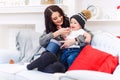 Cute little baby having fun with her mother on the blue sofa in the festive decorated christmas room. Happy winter Royalty Free Stock Photo