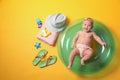 Cute little baby with inflatable ring and beach accessories on yellow background, top view Royalty Free Stock Photo