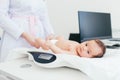 Cute little baby lying on scales, medical checkup in clinic, copy space. Young female blonde pediatrician doctor examines baby Royalty Free Stock Photo
