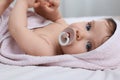 Cute little baby with pacifier in hooded towel after bathing on bed, closeup Royalty Free Stock Photo