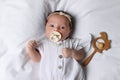 Cute little baby with pacifier and rattle lying on bed, top view Royalty Free Stock Photo