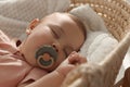 Cute little baby with pacifier sleeping in wicker crib, closeup Royalty Free Stock Photo