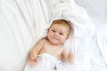 Cute little baby playing with own feet after taking bath. Adorable beautiful girl wrapped in white towels Royalty Free Stock Photo