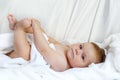 Cute little baby playing with own feet after taking bath. Adorable beautiful girl wrapped in white towels Royalty Free Stock Photo