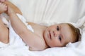 Cute little baby playing with own feet after taking bath. Adorable beautiful girl wrapped in white towels Royalty Free Stock Photo