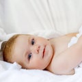 Cute little baby playing with own feet after taking bath. Adorable beautiful girl wrapped in white towels. Happy healthy Royalty Free Stock Photo