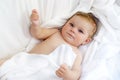 Cute little baby playing with own feet after taking bath. Adorable beautiful girl wrapped in white towels Royalty Free Stock Photo