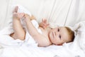 Cute little baby playing with own feet after taking bath. Adorable beautiful girl wrapped in white towels Royalty Free Stock Photo