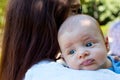 Portrait of beautiful baby with blue eyes and cute face, mother with brown hair caring infant on shoulder, baby burping position Royalty Free Stock Photo