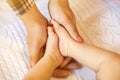 Cute little baby`s legs in mother`s hands close up in bed at home