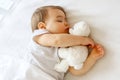 Cute little baby sleeping hugging his white teddy bear