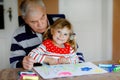 Cute little baby toddler girl and handsome senior grandfather painting with colorful felt pens and pencils at home Royalty Free Stock Photo
