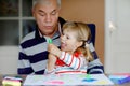 Cute little baby toddler girl and handsome senior grandfather painting with colorful felt pens and pencils at home Royalty Free Stock Photo