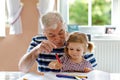 Cute little baby toddler girl and handsome senior grandfather painting with colorful pencils at home. Grandchild and man Royalty Free Stock Photo