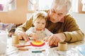 Cute little baby toddler girl and handsome senior grandfather painting with colorful pencils at home. Grandchild and man Royalty Free Stock Photo