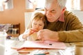 Cute little baby toddler girl and handsome senior grandfather painting with colorful pencils at home. Grandchild and man Royalty Free Stock Photo