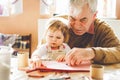 Cute little baby toddler girl and handsome senior grandfather painting with colorful pencils at home. Grandchild and man Royalty Free Stock Photo