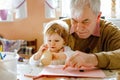 Cute little baby toddler girl and handsome senior grandfather painting with colorful pencils at home. Grandchild and man Royalty Free Stock Photo