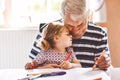 Cute little baby toddler girl and handsome senior grandfather painting with colorful pencils at home. Grandchild and man Royalty Free Stock Photo