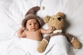 Cute little baby with toy bear lying under blanket in bed, top view Royalty Free Stock Photo