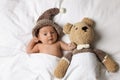 Cute little baby with toy bear lying under blanket in bed, top view Royalty Free Stock Photo