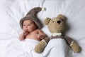 Cute little baby with toy bear lying under blanket in bed, top view Royalty Free Stock Photo