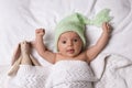 Cute little baby with toy bunny lying under knitted plaid in bed, top view Royalty Free Stock Photo