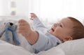 Cute little baby with toy lying in bed under soft blanket indoors Royalty Free Stock Photo