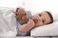 Cute little baby with toy lying in bed under soft blanket indoors Royalty Free Stock Photo