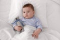 Cute little baby with toy lying in bed under soft blanket, top view Royalty Free Stock Photo