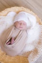 Cute little baby in white knitted hat lies in a wicker basket in a beige knitted blanket. Summer mood. Royalty Free Stock Photo