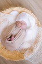 Cute little baby in white knitted hat lies in a wicker basket in a beige knitted blanket. Summer mood. Royalty Free Stock Photo