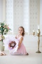 A cute little ballerina in a ballet costume is sitting on the floor with a big flower and smiling. Girl in the dance class. The gi Royalty Free Stock Photo