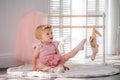 A cute little ballerina in a pink ballet costume sits near the barre in the room and tries to put on her pointe shoes. Kid and Royalty Free Stock Photo