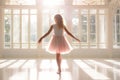 Cute little ballerina wearing pink dress dancing in white sunny studio. Girl in dance class. Child practicing ballet