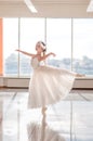 Cute little ballerina in white ballet costume and pointe shoes with is dancing in the room
