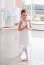 Cute little ballerina in white dress and pointe shoes dreams about ballet dances