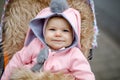 Cute little beautiful baby girl sitting in the pram or stroller on autumn day. Happy smiling child in warm clothes Royalty Free Stock Photo