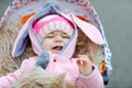 Cute little beautiful baby girl sitting in the pram or stroller on autumn day. Happy smiling child in warm clothes Royalty Free Stock Photo