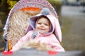 Cute little beautiful baby girl sitting in the pram or stroller on autumn day. Happy smiling child in warm clothes Royalty Free Stock Photo